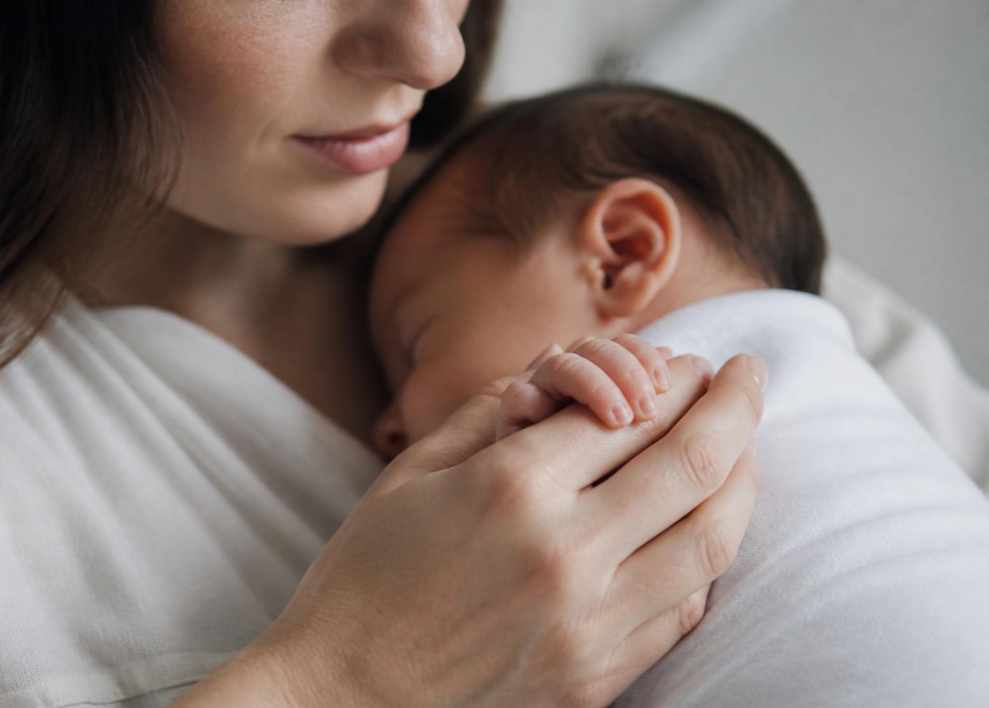 A mother holding her newborn's hand
